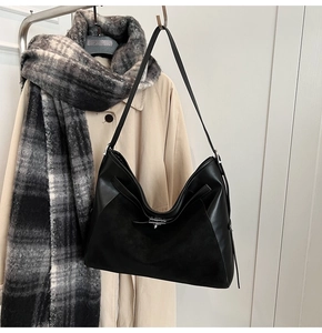 Detail of black Hobo bag with mixed leather texture and silver rotating lock on a coat