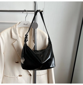 Détail du sac hobo noir brillant avec quincaillerie argentée et breloque en forme de cœur