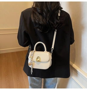 Detail of white leather saddle bag with silk scarf handle and gold hardware on model