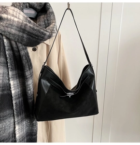Detail of black tote bag showing premium leather and suede texture with silver buckle