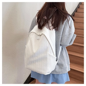 Close-up of white backpack showing woven jacquard texture and side pocket on stairs