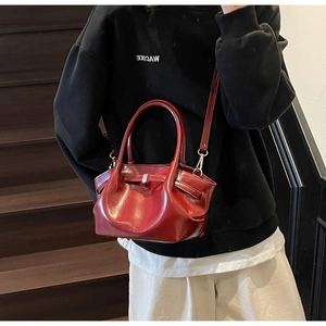 Dettaglio di borsa tote in pelle rossa con pieghe e finitura lucida su modella