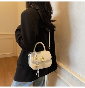 Detail showing creamy white saddle bag with horseshoe buckle and silk scarf on model