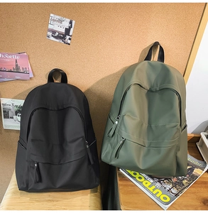 Detail of minimalist school backpacks in black and olive green on a wooden desk