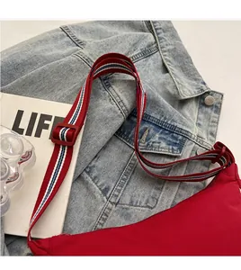Detail of adjustable red, white, and blue striped shoulder strap on red nylon crossbody bag