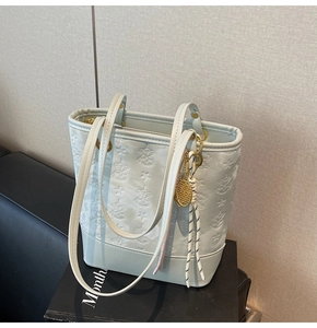 Detail view of mint blue leather tote with star embossing and a tennis racket charm