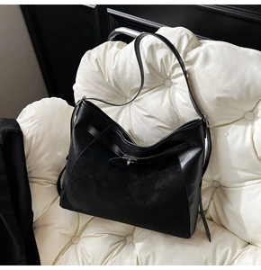 Detail of black leather and suede stitching on tote bag with metal twist lock closure