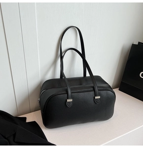 Detailed close-up of black lychee grain texture and silver metal hardware on a boston bag