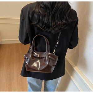 Dettaglio borsa tote in pelle lucida marrone scuro con trama vintage e fibbia dorata