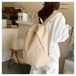 Close-up of beige woven backpack texture with adjustable strap and metal zipper detail