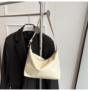 Détail du sac porté épaule en croissant avec pendentif coeur argenté et finition crème