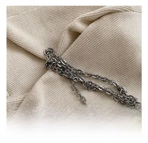 Détail macro de la chaîne en métal argenté poli sur le sac seau plissé beige texturé
