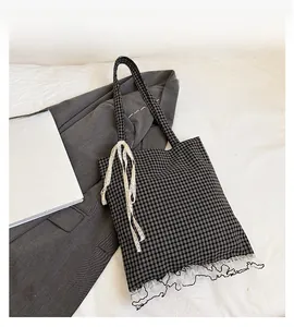 Close-up of black and white checkered canvas tote bag with delicate lace trim detail
