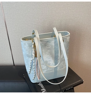 Detail of light blue embossed star pattern shoulder bag with braided rope charm