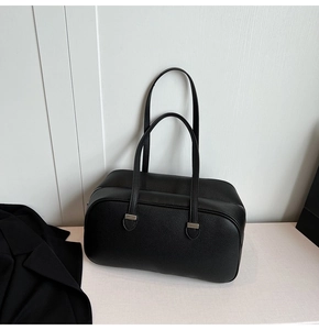 Close-up of black lychee grain leather boston bag with silver hardware and long handles