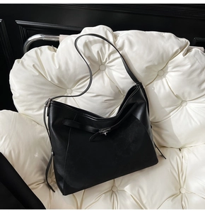 Detail of a black leather hobo bag with silver buckle on a white leather background