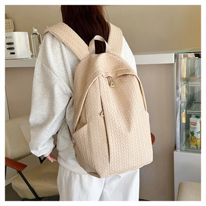 Detail view of the beige herringbone textured backpack showing wide straps and multi-pockets