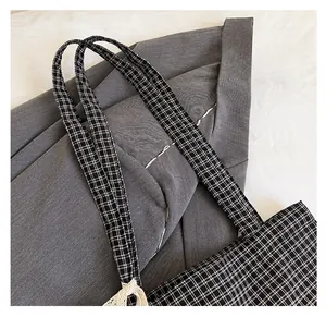 Detail of checkered tote bag strap with delicate lace trim on canvas material
