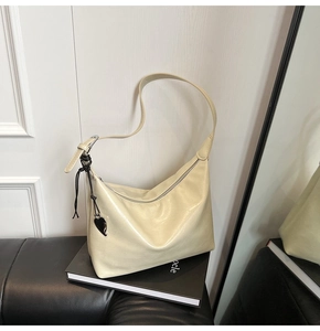 Gros plan du sac beige sous le bras sur un livre avec breloque cœur et cuir brillant
