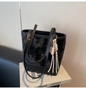 Close-up of black bucket bag with star embossing and pink braided leaf charm