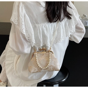 Detail of embroidered floral handbag featuring golden metal clasp and pearl chain straps