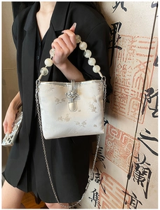 Détail du sac en satin brodé de fleurs avec fermoir nœud chinois et poignée en perles