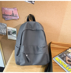 Detailed view of deep grey water-resistant backpack with front zipper on a wooden bench