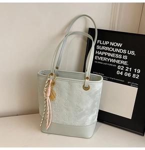 Detail of light green bucket bag with star embossing and metal leaf pendant