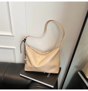 Détail du sac hobo beige avec texture en cuir et pendentif en forme de cœur argenté