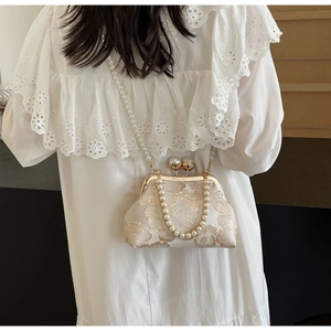 Detailed view of cream jacquard bag featuring pearl handle and vintage metal clasp