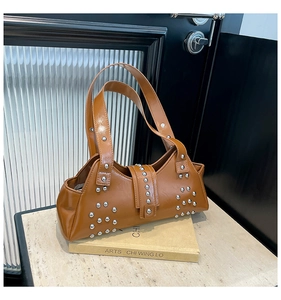 Detail van vintage bruine leren shopper met zilveren klinknagels op een decoratief boek