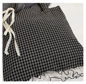 Close-up of black and white checkered tote bag with white lace trim and bow detail
