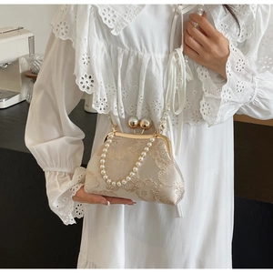Detailed embroidery on vintage-style evening bag with pearl handle and metal clasp