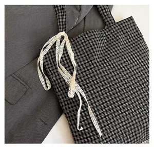 Detailed shot of tote bag featuring white lace ribbon and black and white checkered fabric