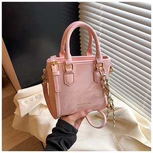 Detailed view of pink bucket bag with gold lettering and decorative woven rope handle