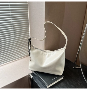 Gros plan du sac hobo en cuir ciré crème avec breloque cœur et détails argentés