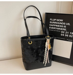 Close-up of black jacquard bucket bag with star patterns and woven rope charm detail