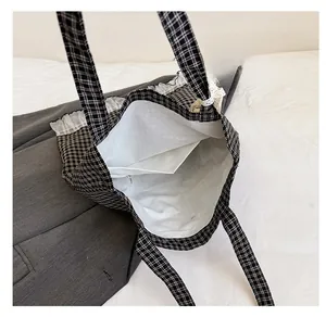 Detail of checkered tote bag with white lace trim and zippered interior pocket