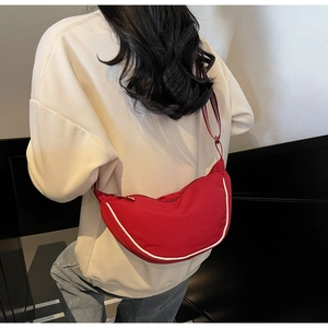 Rear view of a model wearing the red nylon crescent bag with white piping and zipper detail