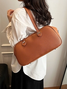 Minimalist caramel leather underarm bag featuring a pebble texture and silver buckle