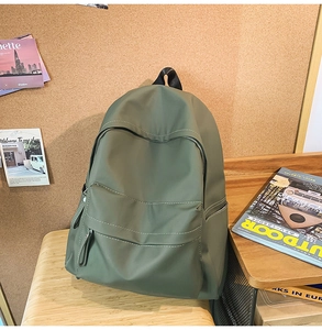 Macro detail of dark green backpack featuring nylon fabric and multi-pocket zipper design