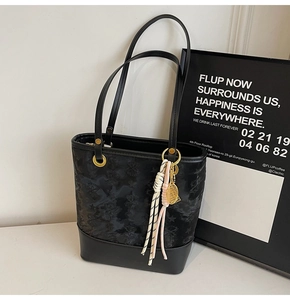 Detail of black patchwork shoulder bag with star embossing and tassel pendant