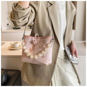 Vue détaillée du sac en satin rose avec broderie florale et grande poignée perlée