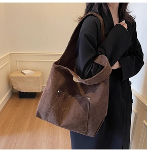 Macro view of dark brown corduroy tote bag showing large front pocket and contrast stitching