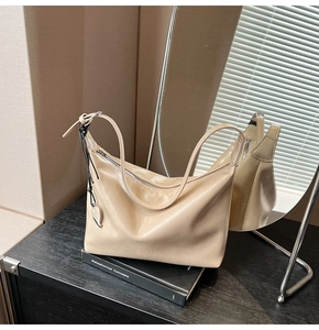 Détail du sac hobo beige avec texture en cuir lisse et pendentif en cœur argenté