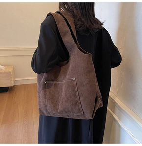 Close-up of brown corduroy tote bag showing vertical texture and metal rivet detail