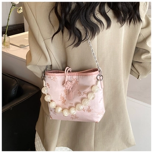 Détail du sac en satin rose avec imprimés floraux et bandoulière en perles