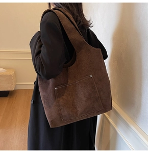Detail of vintage brown corduroy tote bag with front pocket and metal rivets on shoulder