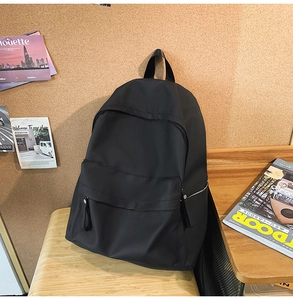 Detail shot of a black nylon backpack on a wooden bench with lifestyle background