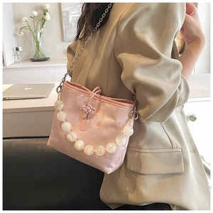 Détail du sac seau en satin rose avec poignée en perles et texture de tissu jacquard